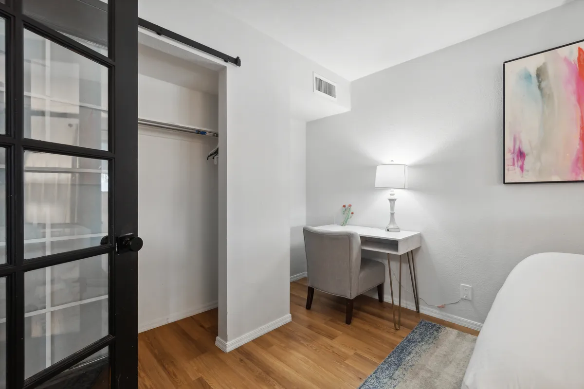 A serene workspace setup inside, featuring a desk with a lamp, comfortable chair, and inspirational artwork. The area is organized and bathed in soft natural light, ideal for productive work sessions or creative brainstorming.